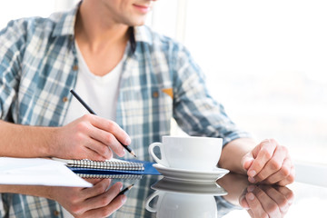 Pensive man drawing and drinking coffee in office