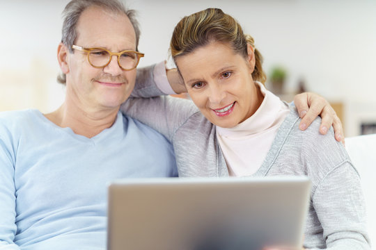 glückliches älteres ehepaar schaut gemeinsam auf laptop