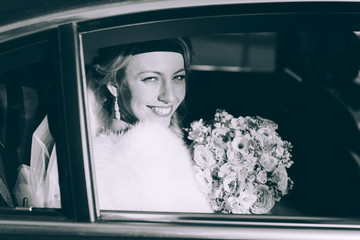 Portrait of a pretty bride with bouquet of roses in a car