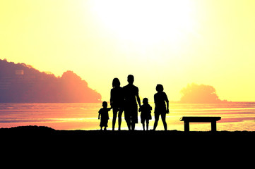 The family walking at the beach with big orange sun light, concept of happy family, every one need family
