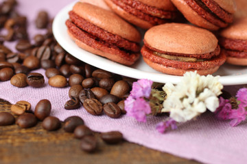 macaroons on a plate with flowers on a purple napkin on a wooden table.