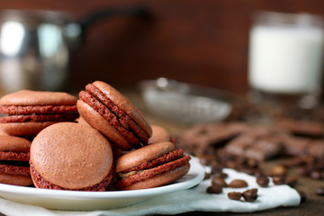 macaroons on plate on napkin with coffee beans on wooden table.