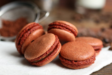 macaroon on a napkin with scattered coffee beans and chocolate on wooden table with sieve