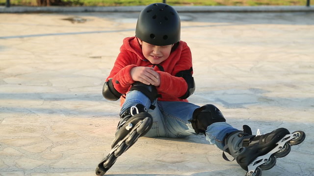 Wounded Child With  Protective Equipment Falling Off Roller Skate