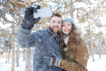 Couple making photo on smartphone in winter park