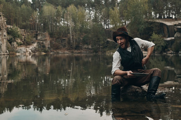 unshaved golddigger washes gold in the lake with rocky bank 