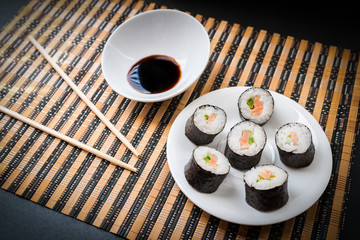 Rolls with salmon in white dish with chopsticks. Selective focus.