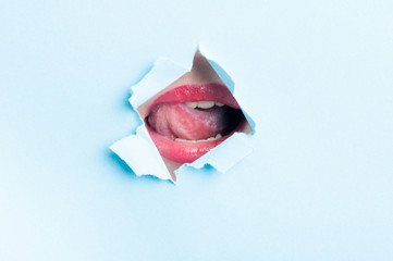 Woman sexy mouth wearing gloss thru ripped paper hole