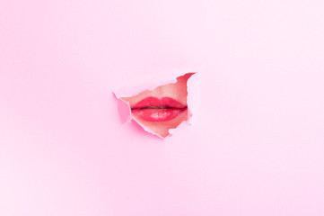 Woman mouth with red lips thru torn cardboard