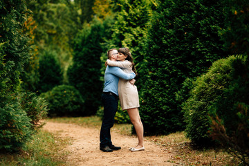 Fototapeta na wymiar Pregnant beautiful woman and her handsome husband lovely hugging in autumn park.