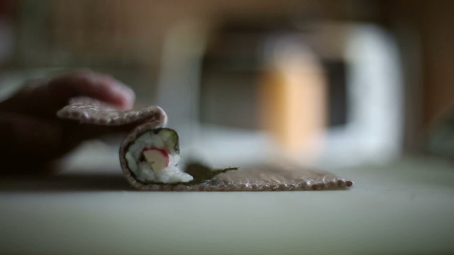 A sushi chef prepares rolls with a bamboo mat, cooking techniques
