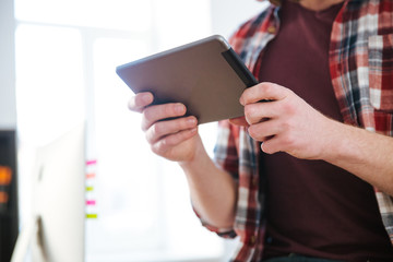 Closeup of tablet used by man in checkered shirt