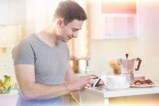 Mann informiert sich morgens beim Kaffee mit Tablet online
