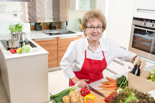 Seniorin freut sich aufs kochen mit frischem Gemüse