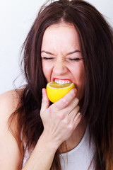 Sour lemon,attractive young girl tasting lemon