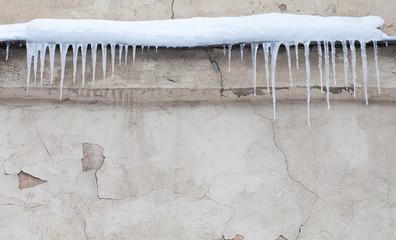 Icicles on the roof. Vintage shabby wall background. Cold winter weather concept. Soft focus