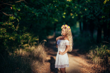 Portrait of blonde girl wearing  white dress with flower wreath