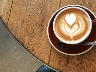 Flat white latte art on wooden table close up