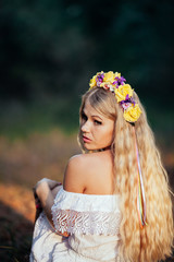 Portrait of blonde girl wearing  white dress with flower wreath