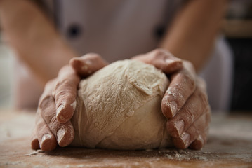 Woman cooking bread dough on wooden desk with flour. Home cuisine, handmade meal. 