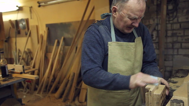man sandpaper grinds wood 