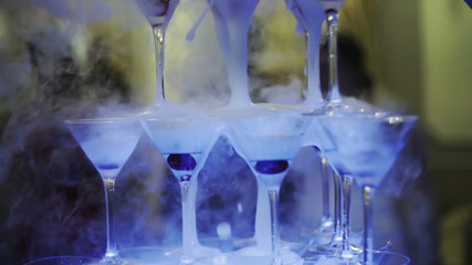 Beautiful pyramid line of different colored alcohol cocktails with mint on a open air party, tequila, martini, vodka, and others on decorated catering bouquet table on open air event