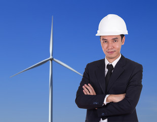 engineer in helmet with arms crossed, wind turbine background