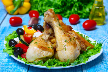 roasted chicken legs with potatoes with Greek salad on wooden background with vegetables
