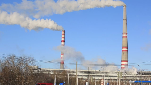 Thermal power plant in sunny cold day. Industrial smoke from the pipes against blue sky.