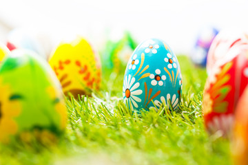 Colorful hand painted Easter eggs in grass. Spring theme, white copy-space