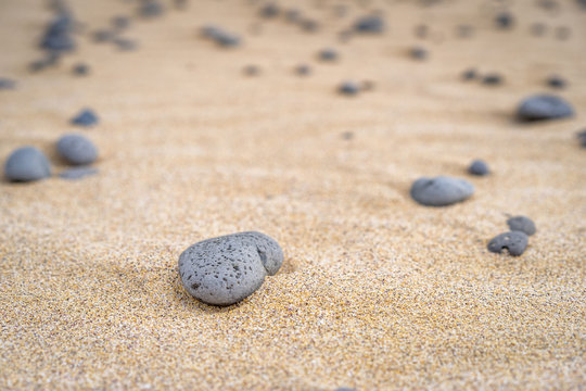 Macro view of grey stone in yellow sand.