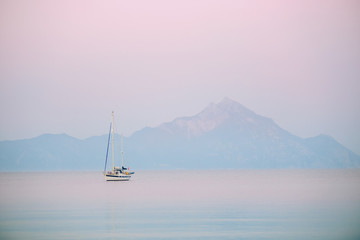 Naklejka premium Yacht and blue water ocean with Athos mountain in the background - Greece, Europe