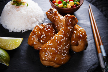 Fried chicken legs with teriyaki sauce sesame seeds and rice on  black stone