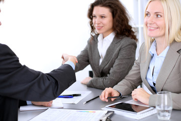 A group of business people at a meeting on the background of office. Business handshake. Focus on a beautiful blonde