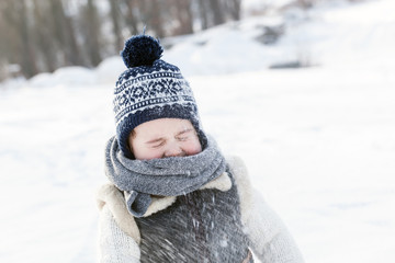 Little boy playing with snow in winter.