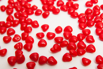 red cinnamon candy hearts on a white background with a shallow depth of field