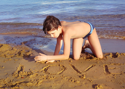 boy on the beach take sun bathing play with sand