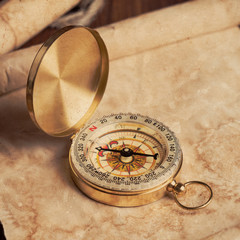 old unrolled map, rolled map and compass on wooden table