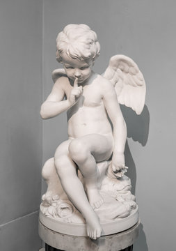 young and sad Angel sitting on a pillar