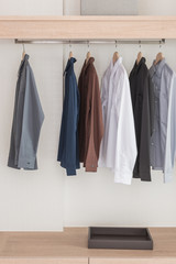 shirts hanging on rail in modern wooden wardrobe