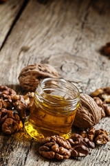 Walnut oil in a small jar and kernels on old wooden background i