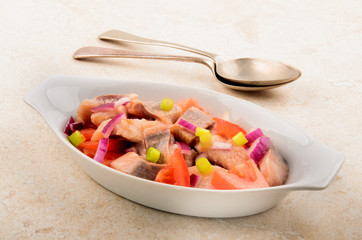 herring salad with lilac onion, spring onion and tomato in a bow