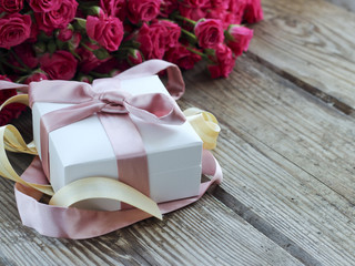 Pink roses and gift box over wooden table, holiday background