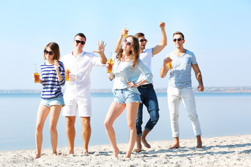 Young people with beer on the riverside