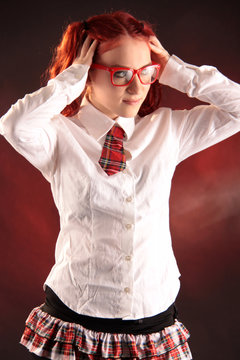 Eine Frau in Schulmädchenuniform und roter Brille im Gesicht