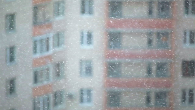 Blizzard with flying snowflakes on buildings backround
