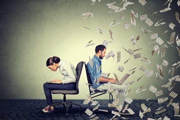 Employee compensation economy concept. Woman working on laptop sitting next to man under money rain.