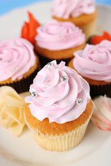 Tasty cupcakes on plate, on color wooden background
