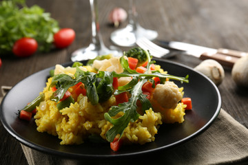 Black plate with vegetable risotto on served wooden table