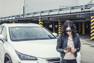 Beautiful sexy female model in leather clothes with a white car